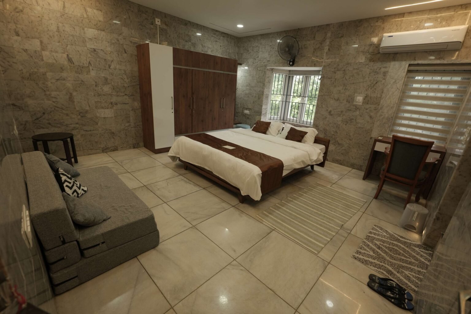 A large bedroom with a double bed, wardrobe, desk and a sofa bed