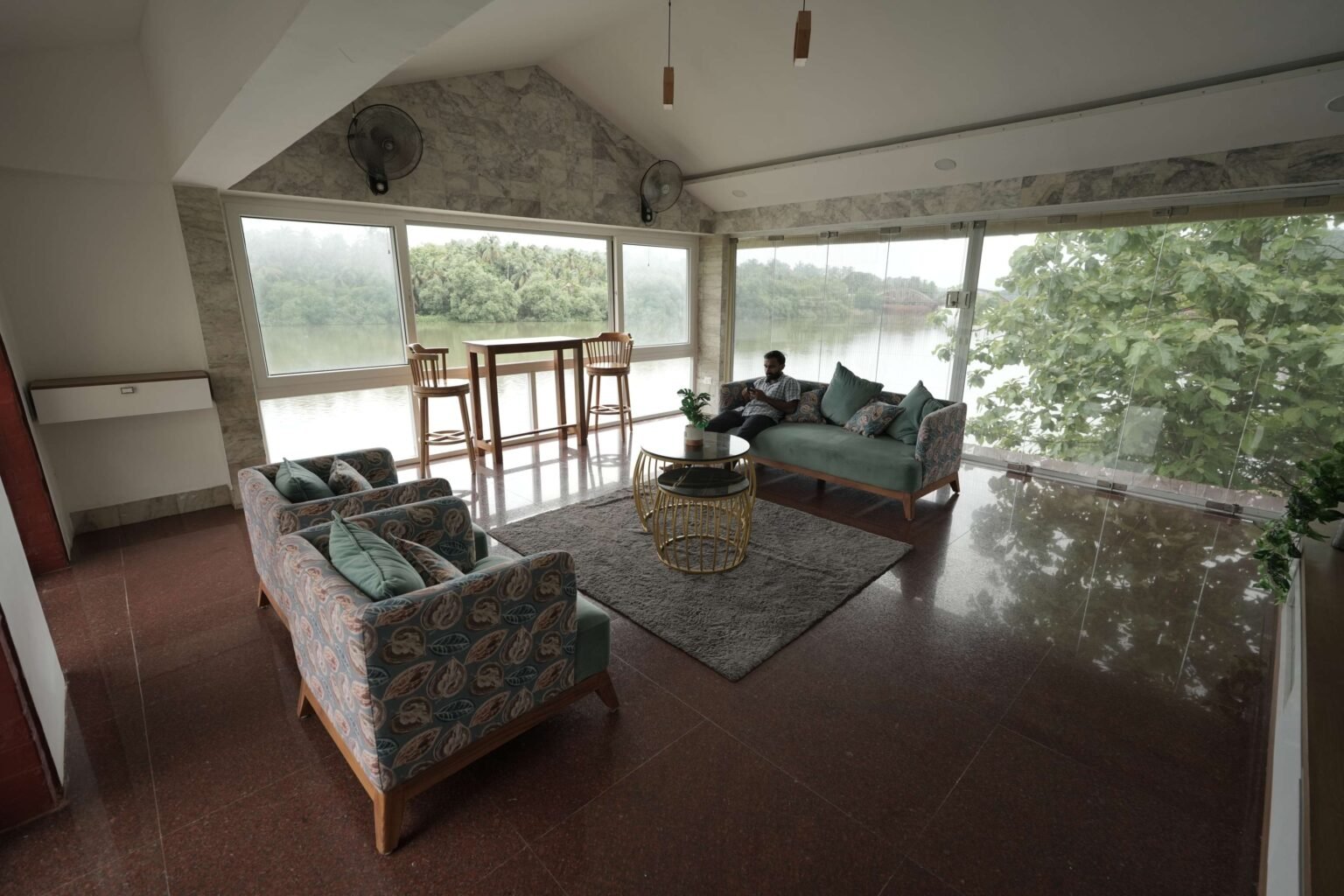 The upstairs lounge with sofas and glass walls on two sides looking over the river